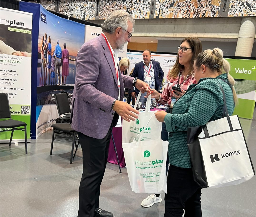 Un représentant de PharmaPlan remet un sac promotionnel à deux participantes du congrès